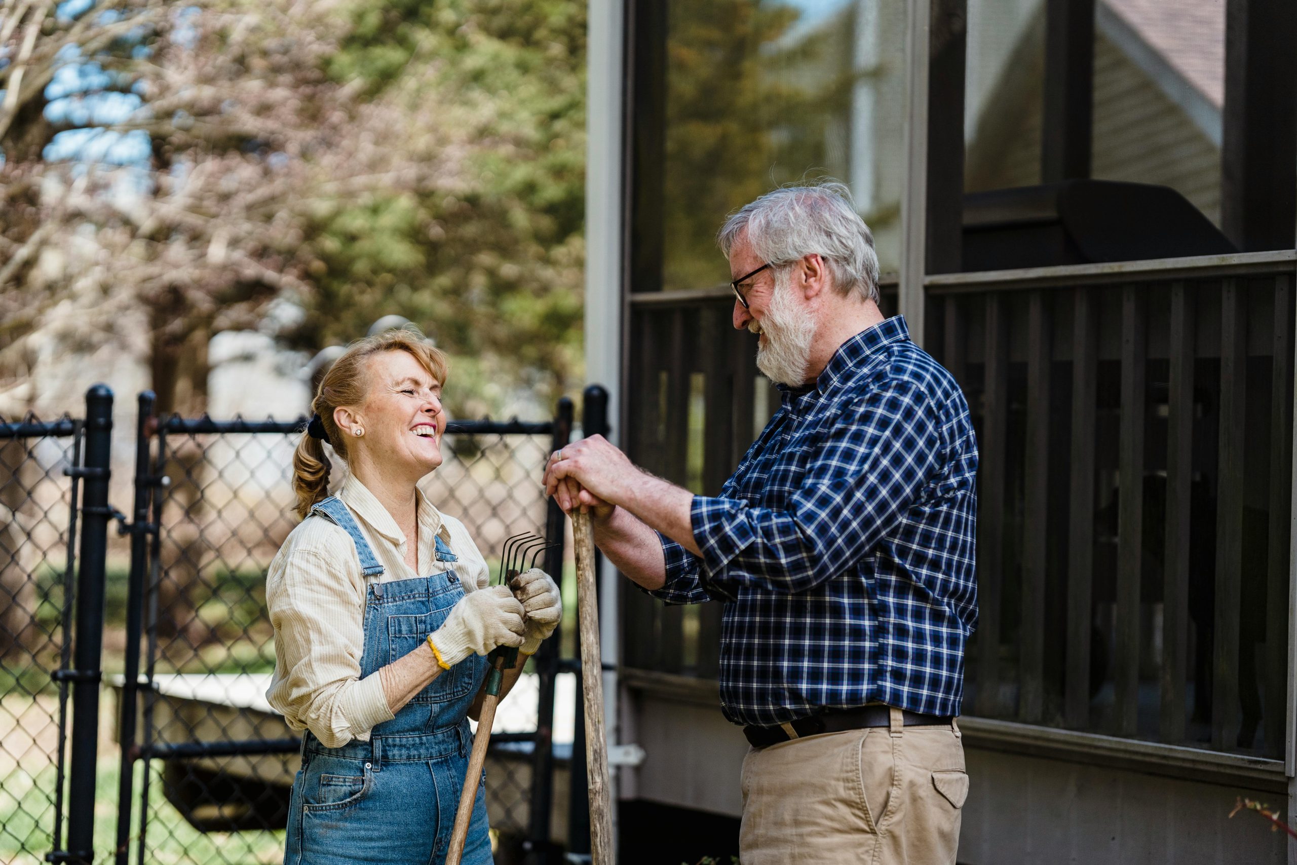 Gardening couple A couple chat in the garden holding gardening tools