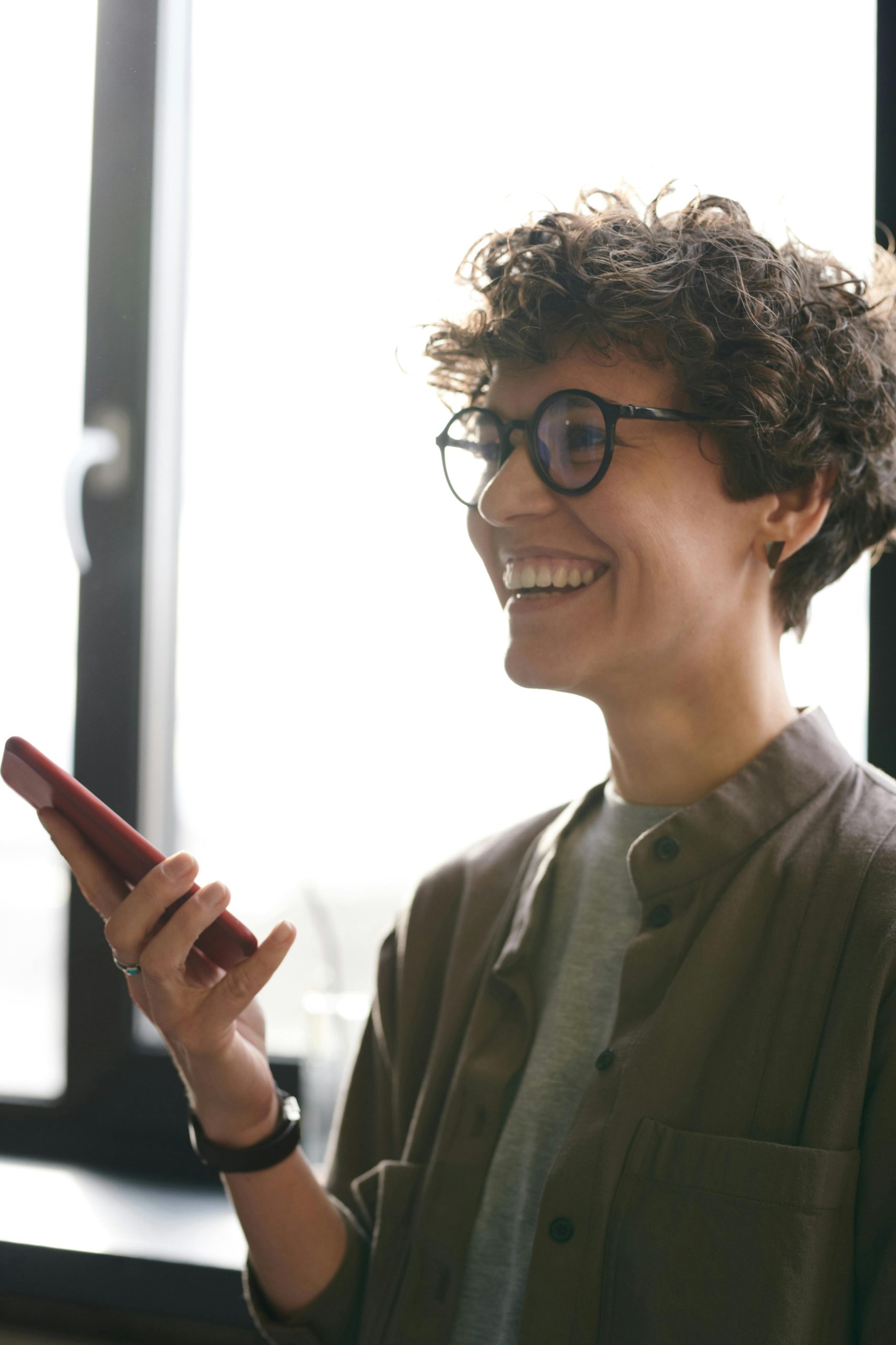 Short style hair lady speaking into smartphone on loudspeaker, smiling
